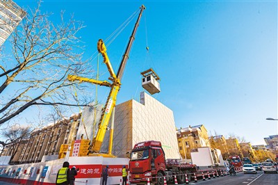 北京市西城區樺皮廠胡同8號樓改造項目現場，汽車吊在吊裝房屋建筑模塊。