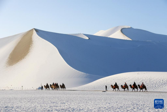 游客在鳴沙山月牙泉景區欣賞雪景。新華社發（張曉亮攝）