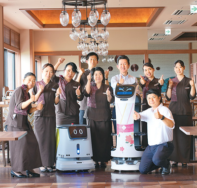 日本餐廳經營者與送餐機器人“貝拉”和清潔機器人CC1合影。   採訪對象供圖