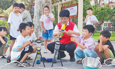 刘华东和小朋友们在做科学实验。   资料照片