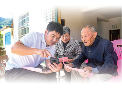 江西宜春市銅鼓縣三都鎮西向村駐村第一書記在協助村民用手機繳納2025年醫保費用。周  亮攝（人民視覺）