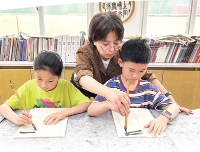  杭州春芽实验学校老师指导春假托管学生练习书法。本报记者 刘军国摄