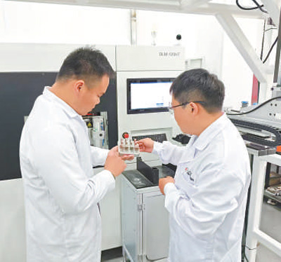 科研人員在檢查“材料數據工廠”高通量設備制備的多組元合金樣品。 中國鋼研供圖