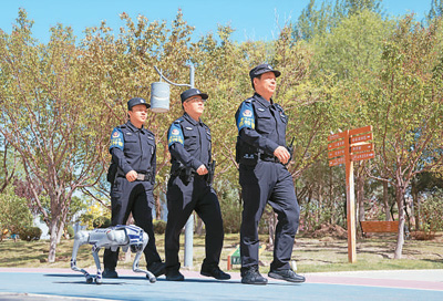 5月9日，在甘肃省金昌市金川区龙首湖公园，一只警用机器狗和民警一起开展例行巡逻。 张宏斌摄（人民图片）
