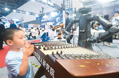 6月22日，小观众在2025杭州国际人形机器人与机器人技术展览会上观看人形机器人弹奏扬琴。   龙 巍摄（人民视觉）