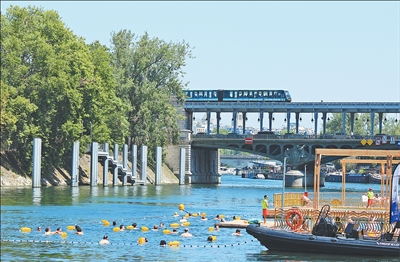 近期，法國巴黎遭遇嚴重熱浪。巴黎塞納河最近開放3處公共游泳區域，供市民和游客度過炎炎夏日。圖為日前，人們在塞納河消暑休閑。   本報記者  尚凱元攝