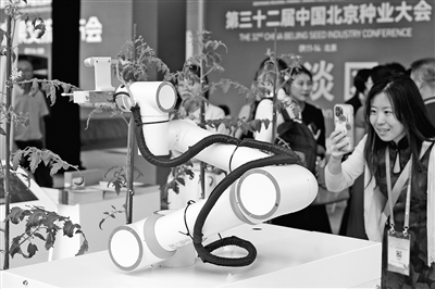 图为观众在展区观看中国科学院遗传与发育生物学研究所科研团队研发的世界首台可自动巡航杂交授粉育种机器人。本报记者 洪星摄