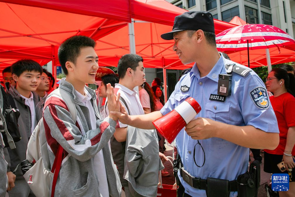 6月20日，在浙江省温州市第二十七中学考点外执勤民警为考生加油打气。  新华社发（刘吉利 摄）