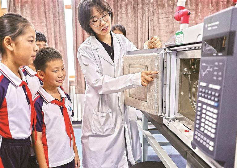 图为工作人员为学生介绍环境空气和废气监测设备的工作原理。曹建雄摄/光明图片