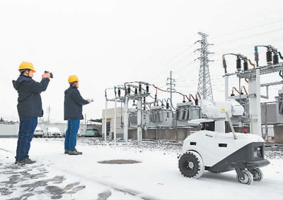 2月2日，在安徽省亳州市220千伏谯城变电站，一台5G智能机器人和国网亳州供电公司运维人员正在对供电设备进行巡视巡查。梁西海摄（人民图片）