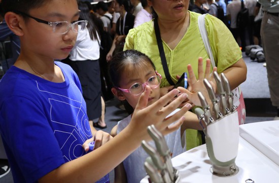 7月5日，在2024世界人工智能大會，小朋友在傲意科技機器人靈巧手展品旁參觀。新華社記者 方喆 攝