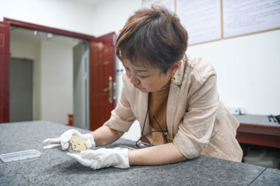 成都金沙遺址博物館副館長、中國文物學會玉器專業委員會副主任王方在鑒賞玉石上陽刻的側身人像（2024年7月10日攝）。新華社記者 王曦 攝