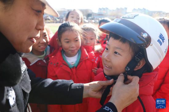 12月2日，在河北省唐山市豐潤區迎賓路小學，民警教學生如何正確佩戴頭盔。新華社發（朱大勇攝）