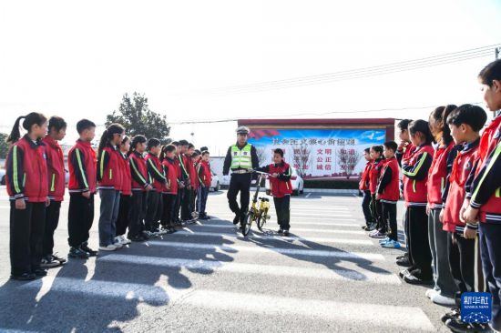 12月2日，在河南省濟源市五龍口鎮實驗小學，濟源市公安局交通警察支隊的民警指導小學生安全過“斑馬線”。新華社發（苗秋鬧攝）