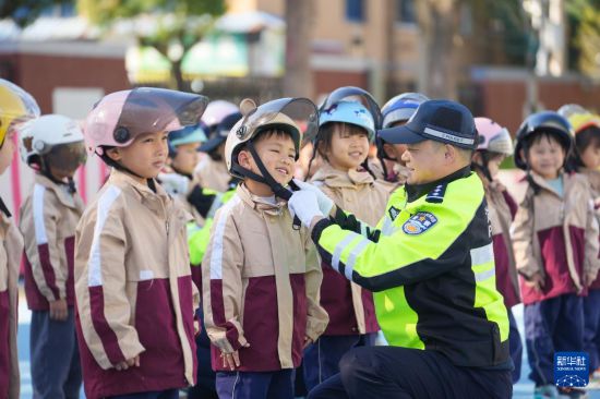 12月2日，在浙江省湖州市德清縣鐘管鎮中心幼兒園，鐘管鎮交警中隊民警指導孩子們如何正確佩戴安全頭盔。新華社發（王正攝）