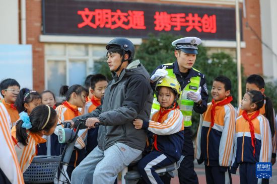 12月2日，在山東省青島汾陽路小學，青島交警李滄大隊民警向學生講解如何安全騎乘電動摩托車。新華社發（張鷹攝）