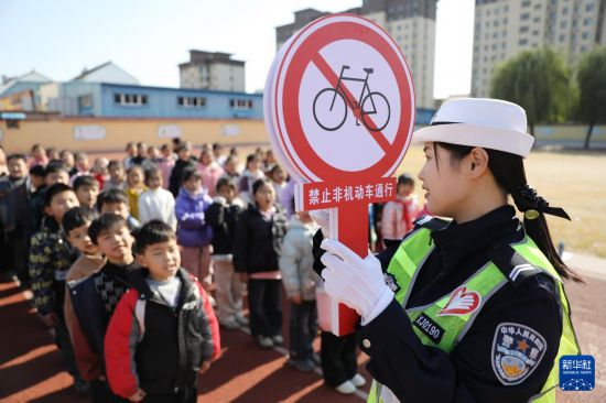 12月2日，河南省焦作市溫縣交警大隊民警在溫縣第二實驗小學指導學生認識交通標識。新華社發（徐宏星攝）