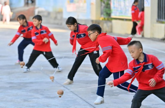 在广西梧州市大桥小学，学生们在体育课上练习打陀螺（2024年10月25日摄）。新华社记者 黄孝邦 摄