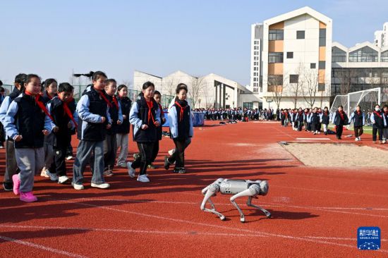 2月19日，在江苏省昆山市信义小学，机器狗带领学生在大课间活动跑步。新华社发（王须中摄）