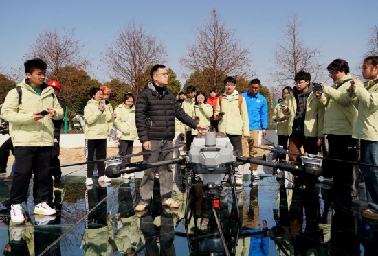  2月18日，在上海昆秀水产专业合作社，行业导师许翔为学生介绍用于播撒饲料、施肥的植保无人机。新华社记者 刘颖 摄