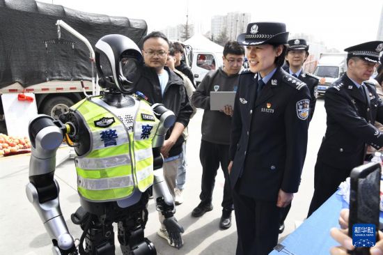  3月24日，一名女警官與警用機器人進行語音交流演示。新華社記者 李紫恆 攝