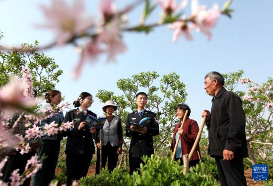 4月13日，在山東省臨沂市平邑縣武台鎮孫家庄村，民警在田間為村民講解國家安全相關知識。新華社發（武紀全攝）