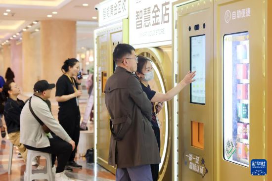 5月5日，在上海市普陀区一家商场内的“智慧金店”，工作人员为市民介绍自助黄金购买设备上的黄金商品。新华社记者 王翔 摄