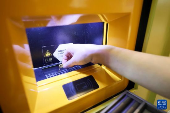 5月5日，在上海市普陀区一家商场内的“智慧金店”，工作人员将用户的黄金首饰放入智能黄金回收设备中。新华社记者 王翔 摄