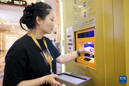 5月5日，在上海市普陀区一家商场内的“智慧金店”，工作人员将用户的黄金首饰放入智能黄金回收设备中。新华社记者 王翔 摄