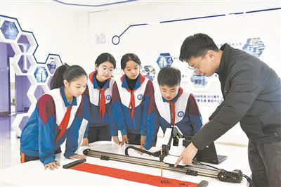 在山东日照金海岸小学，老师指导学生练习机械臂毛笔书写编程。