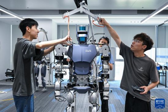 6月30日，在武汉格蓝若智能技术股份有限公司，华中科技大学博士研究生钱乐天（右一）和团队成员准备对“劳动者”系列人形机器人进行调试。新华社记者 杜子璇 摄
