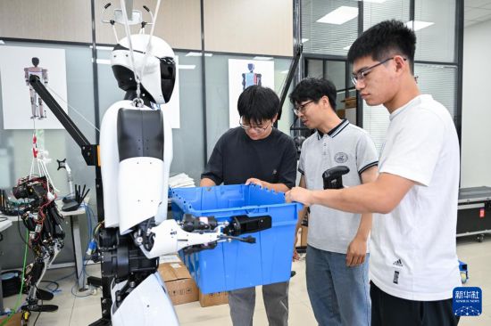 5月29日，在华中科技大学机械科学与工程学院，博士研究生丁涛（右二）和团队成员在对“荆楚”人形机器人进行搬运测试。新华社记者 杜子璇 摄