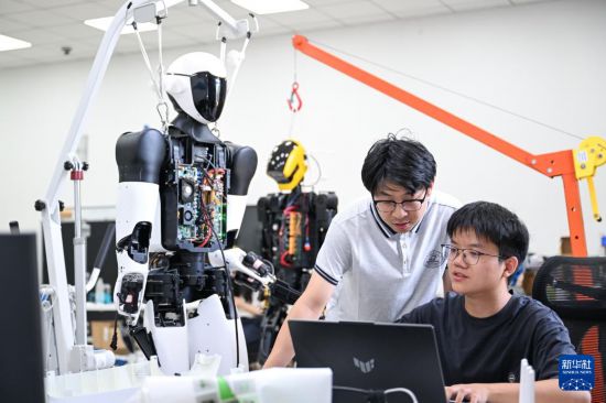 5月29日，在华中科技大学机械科学与工程学院，博士研究生丁涛（右）与硕士研究生夏天对“荆楚”人形机器人进行代码调试。新华社记者 杜子璇 摄