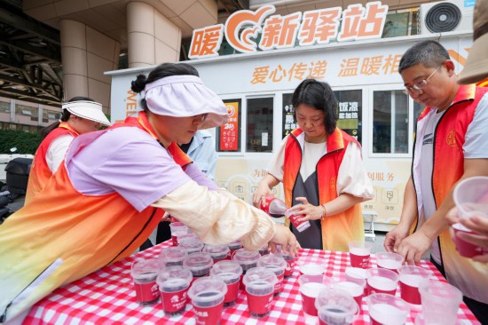 6月25日，在北京市東城區崇外街道一處“暖新驛站”外，街道工作人員在為高溫下的外賣員、快遞員准備冰鎮飲料。新華社記者 鞠煥宗 攝