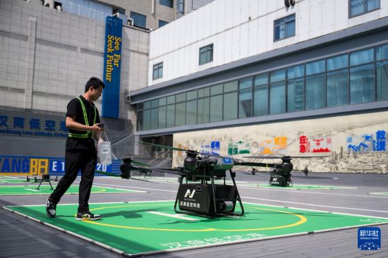 6月16日，在汉商低空港停机坪，一名工作人员给无人机装配货物。新华社记者 伍志尊 摄