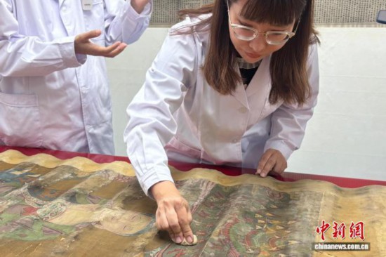 文物修复师在北京大运河博物馆用传统方法对灰尘污渍严重的书画进行粘附除尘。 中新社记者 徐婧 摄