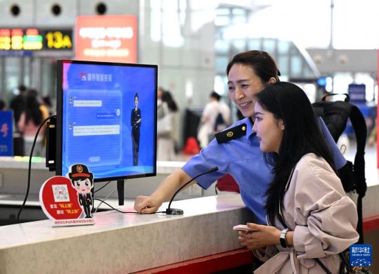 10月5日，在河北石家庄火車站候車大廳服務台，旅客向“AI智能客服機”問詢旅行信息。     新華社發（陳其保攝）
