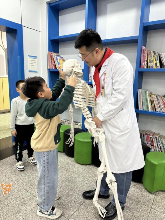 北京協和醫院骨科主治醫師楊陽利用骨骼模型，向學生科普脊柱知識。（北京協和醫院西單院區供圖）