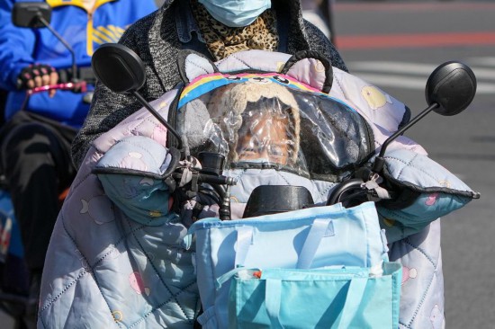 10月18日,一位小朋友在電動自行車的擋風后面躲風。新華社記者 鞠煥宗 攝