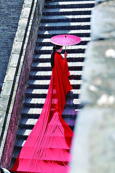 一名游客身着汉服在西安城墙上拍照。近年来，租赁汉服拍写真成为很多游客不可或缺的旅游体验。新华社发