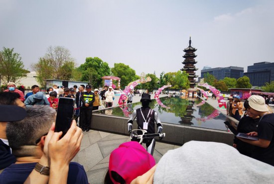 4月10日,一台人形機器人在上海龍華廣場表演吉他彈唱,吸引市民游客駐足拍照。新華社記者 陳愛平 攝