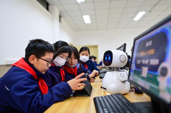 2025年12月5日，杭州市钱塘区学林小学的学生在人工智能通识课上对人工智能机器人进行编程。新华社记者 江汉 摄