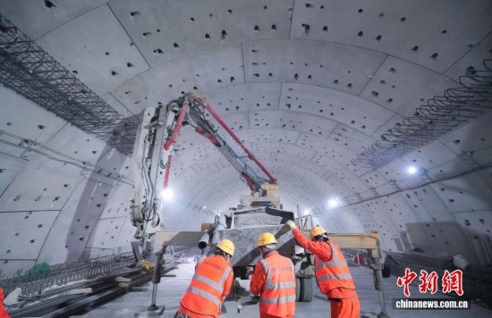 图为3月16日晚，施工人员正在浇筑现浇车道板。据了解，隧道全长约5.75公里，其中盾构段长约3.3公里，采用开挖直径17.5米的“山河号”盾构机施工。中新社发 肖雨 摄